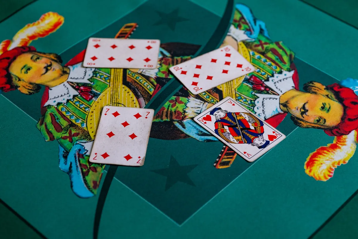 Un pli de belote sur un tapis de cartes : sept, huit et dix de carreau, coupés par le valet de cœur