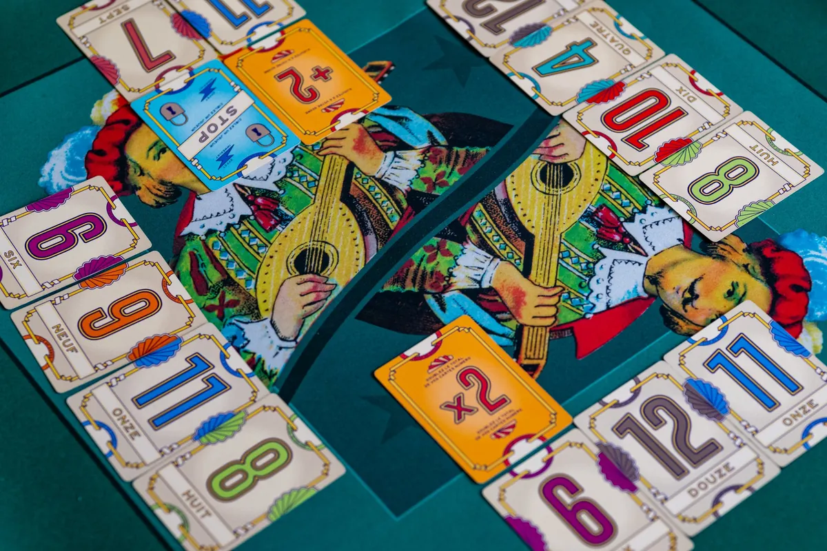 Cartes de Flip 7 étalées autour d’un tapis : chiffres, cartes ×2, +2 et Stop